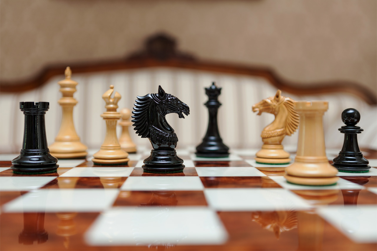 Apollo lacquered ebony and boxwood chess pieces on a glossy wooden chess board