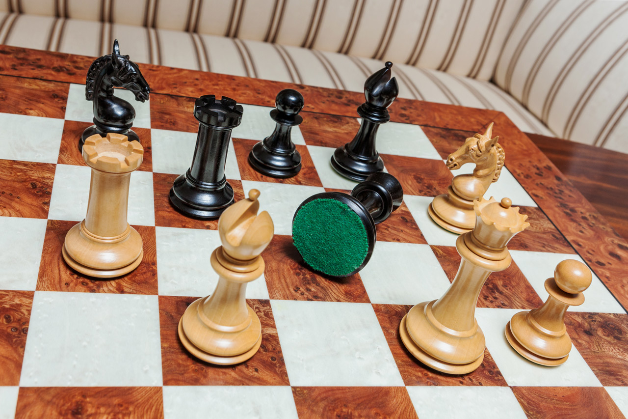 Overhead view of Chevalier ebony and boxwood chess pieces with a green felt base on the 60 cm Toscana chess board