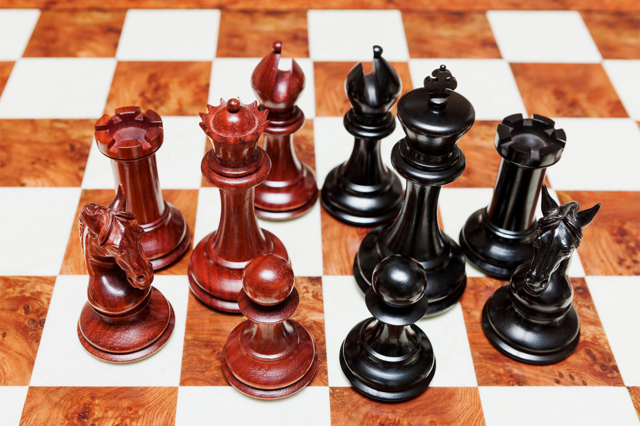 Overhead view of Chevalier padauk and ebony chess pieces on the 60 cm Toscana chess board