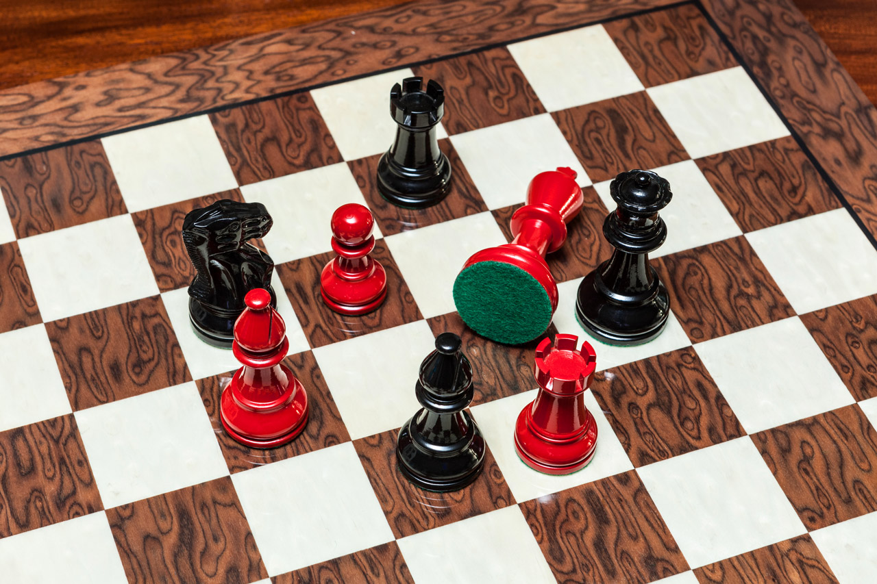 Overhead view of Earl red and black chess pieces with a green felt base on the 50 cm Cordoba chess board