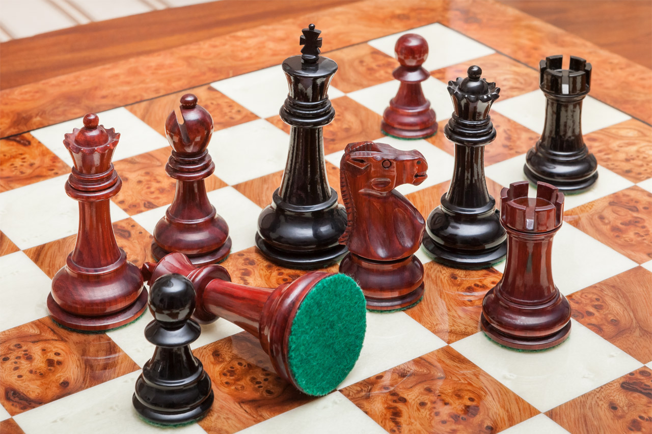 Shown with: 51 cm Venezia chess board Overhead close-up of Viking lacquered padauk and ebony chess pieces with a fallen pawn on the 51 cm Venezia chess board